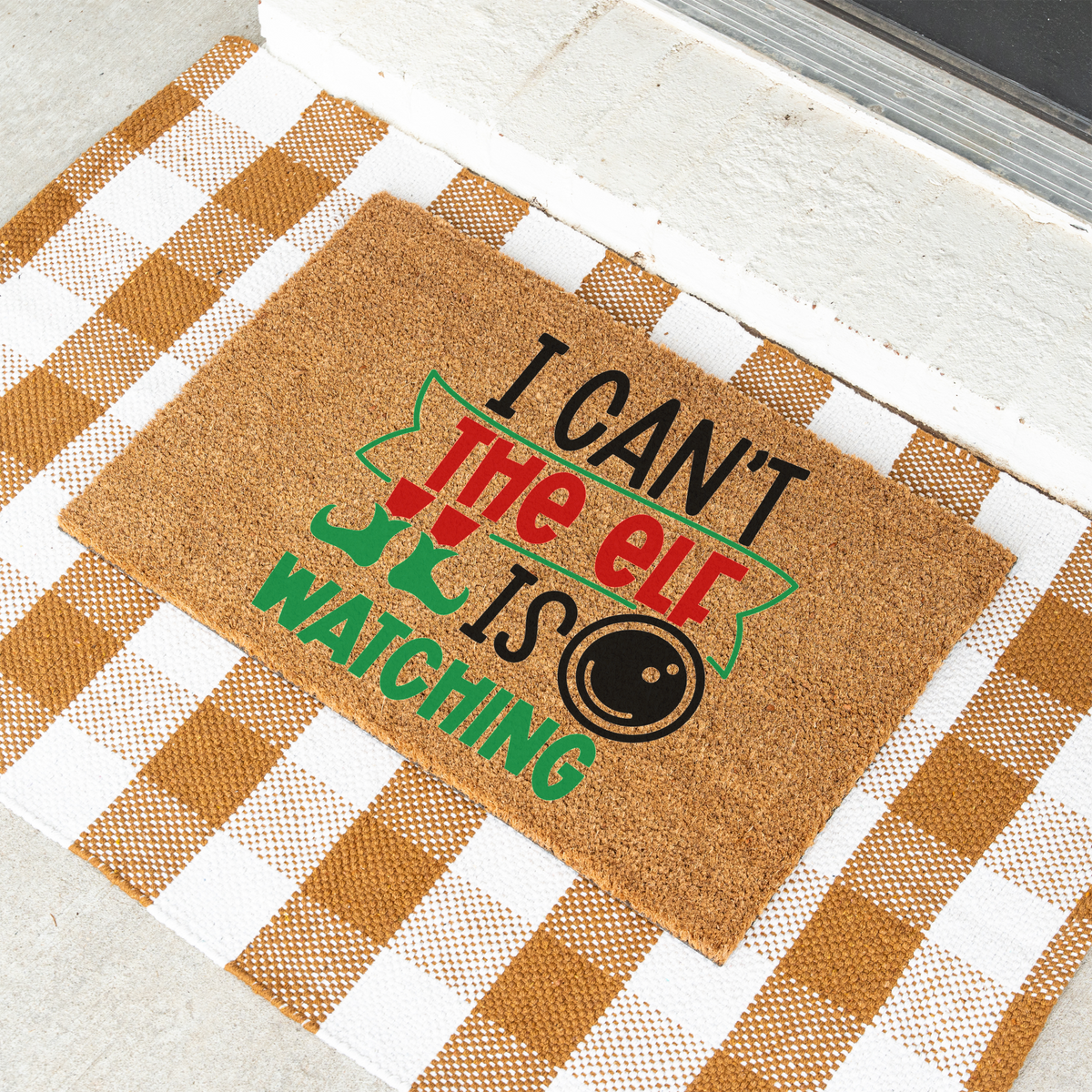 I Can't The Elf Is Watching coir doormat on a tan and white check rug