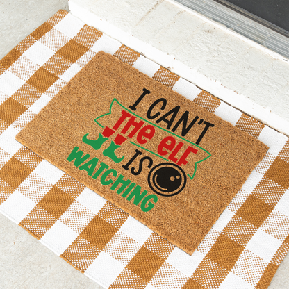 I Can't The Elf Is Watching coir doormat on a tan and white check rug