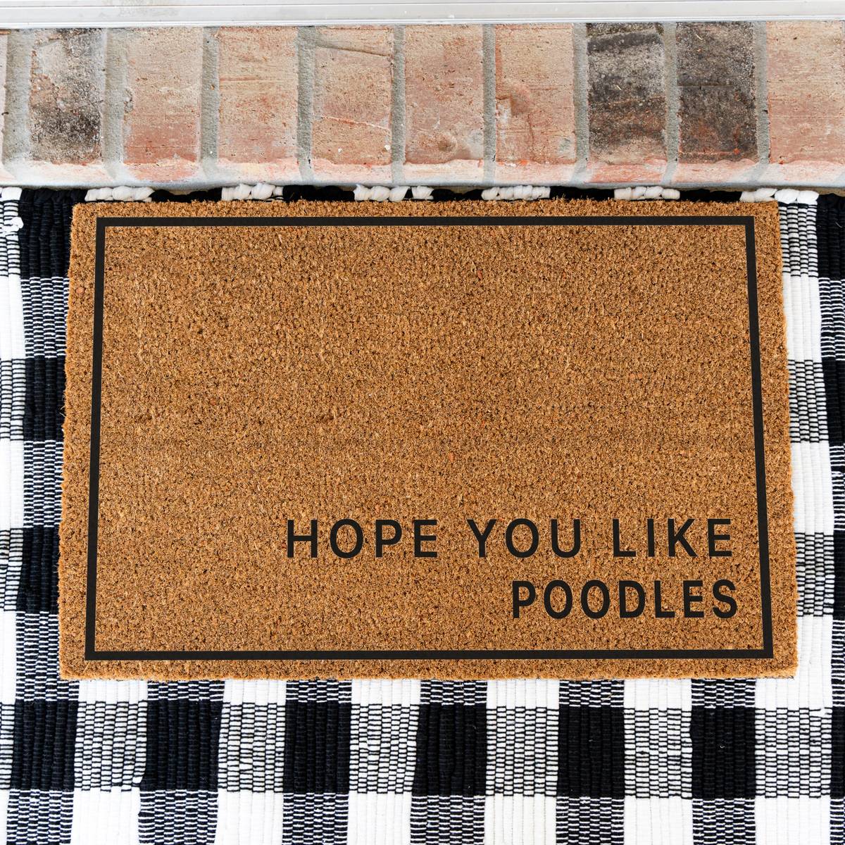 Hope You Like Poodles minimalist coir doormat with a thin black border on a black and white buffalo check rug, close view