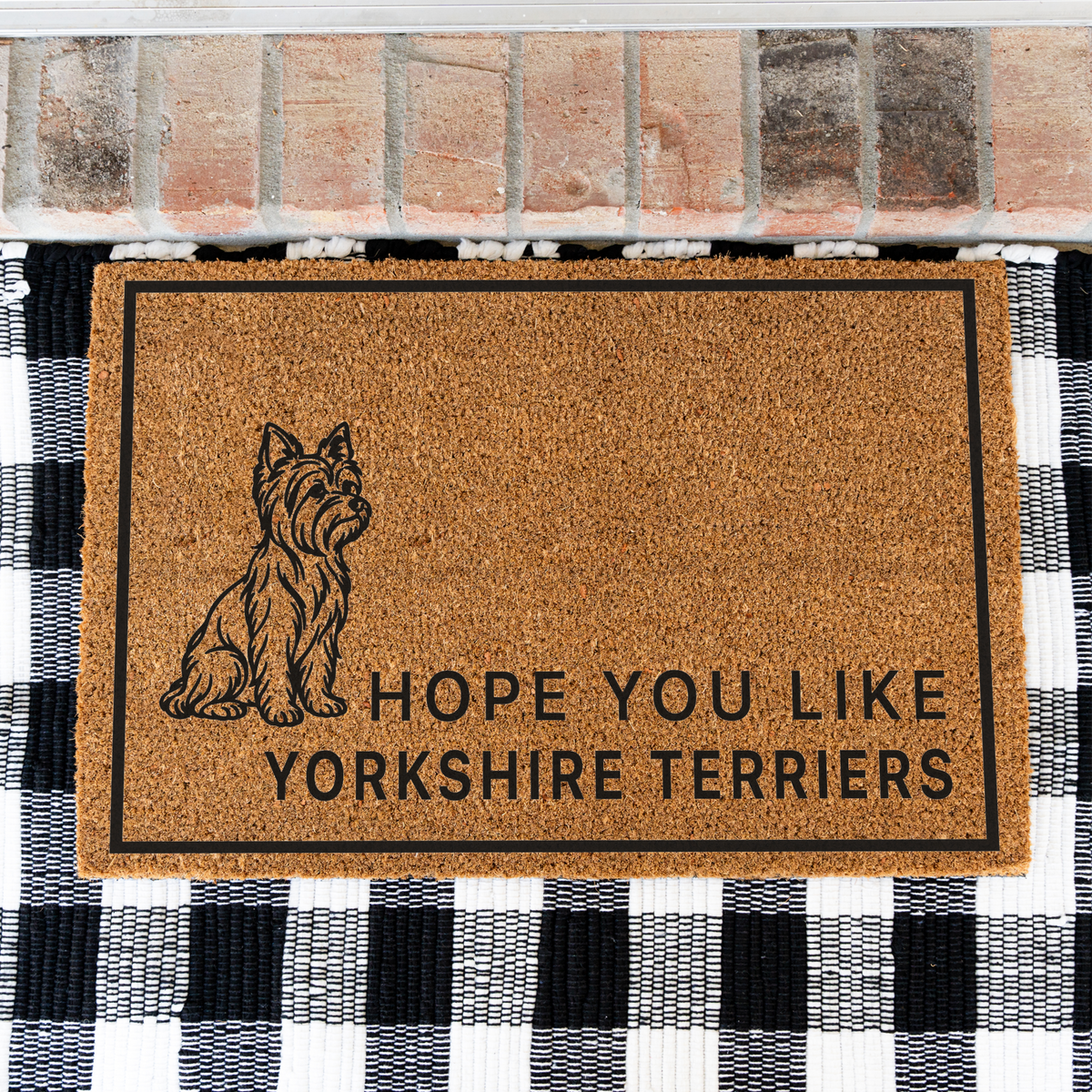 Hope You Like Yorkshire Terriers coir doormat with a drawing of a sitting Yorkshire terrier on a black and white buffalo check rug, close view