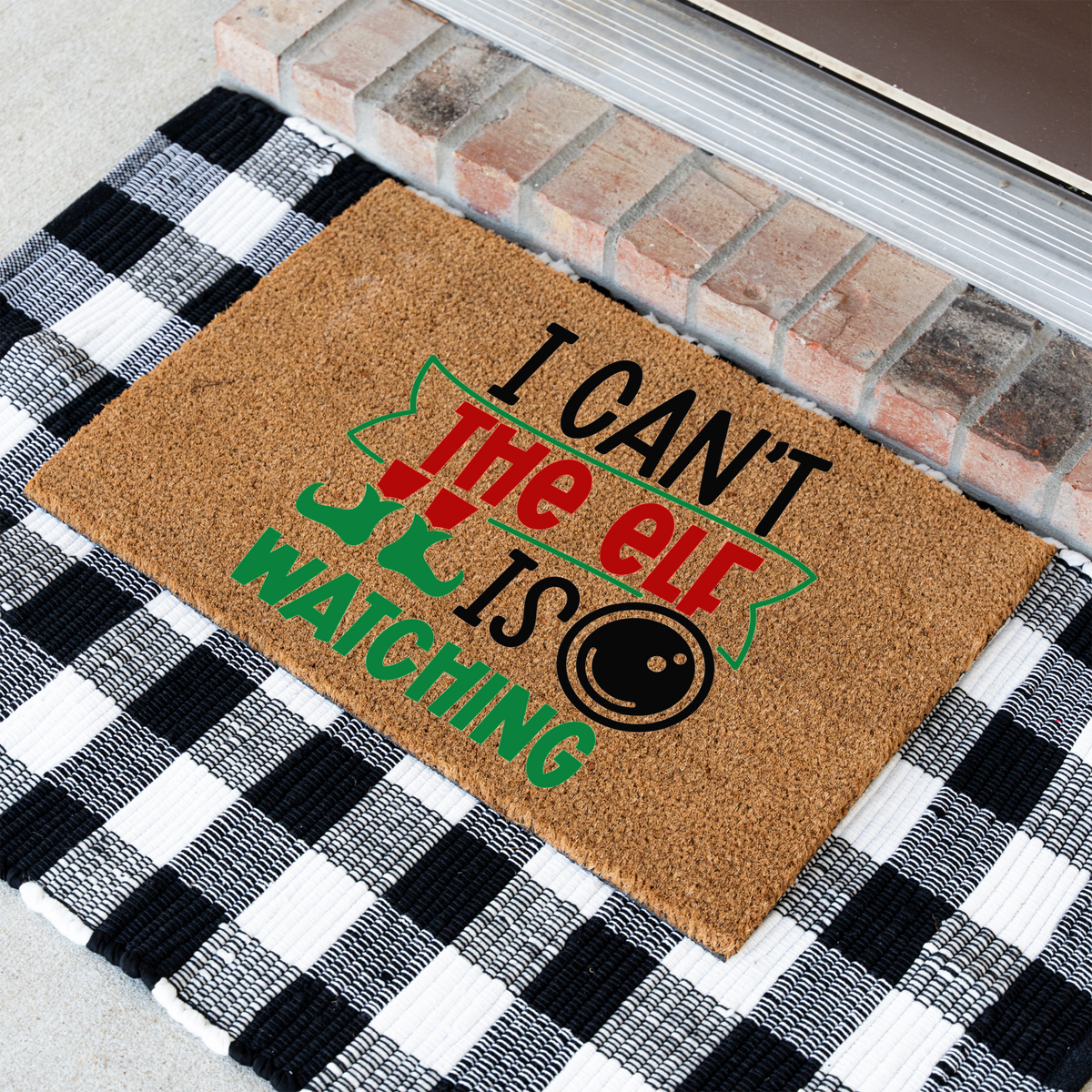 I Can't The Elf Is Watching coir doormat at an angle on a black and white buffalo check rug