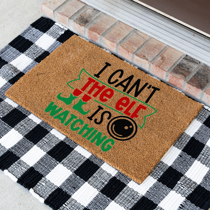 I Can't The Elf Is Watching coir doormat at an angle on a black and white buffalo check rug