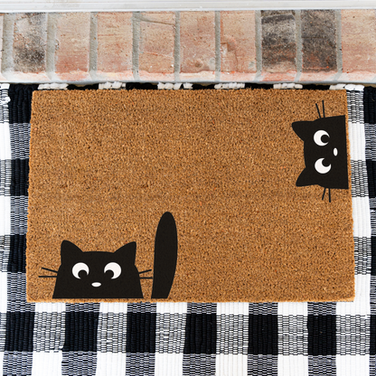 Peeking black cats coir doormat on a black and white buffalo check rug, close view