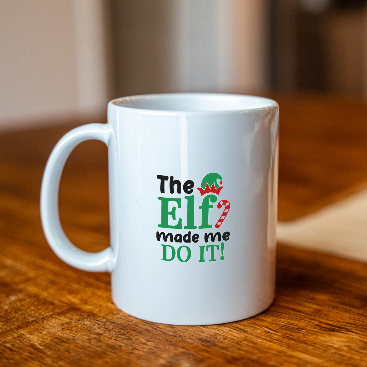 The Elf Made Me Do It white ceramic Christmas coffee mug on a wooden table
