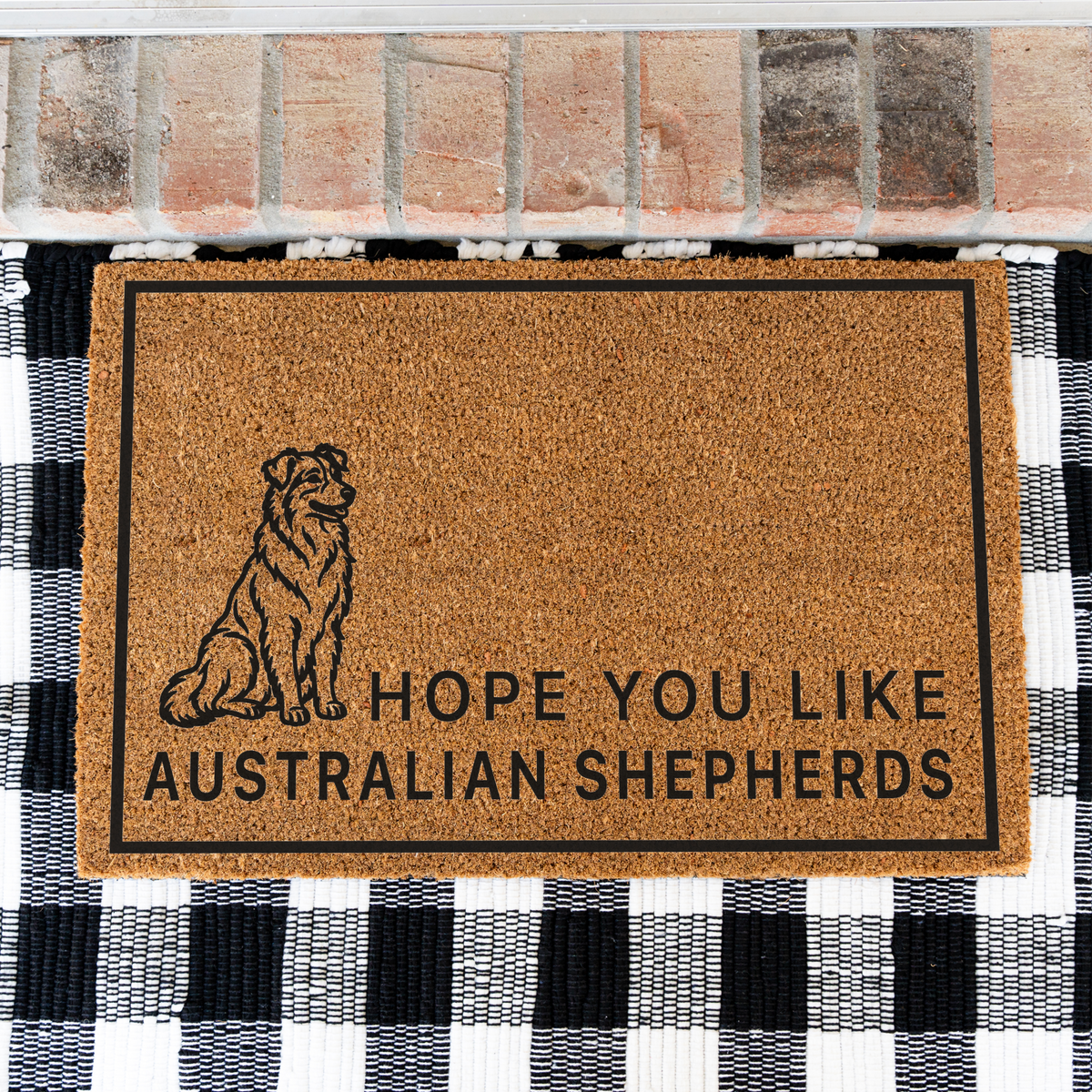 Hope You Like Australian Shepherds coir doormat with a drawing of a sitting Australian shepherd on a black and white buffalo check rug, close view