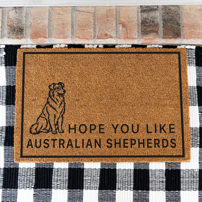 Hope You Like Australian Shepherds coir doormat with a drawing of a sitting Australian shepherd on a black and white buffalo check rug, close view