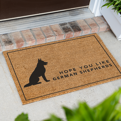 Hope You Like German Shepherds silhouette coir doormat with a thin black border at an angle in front of a brick step