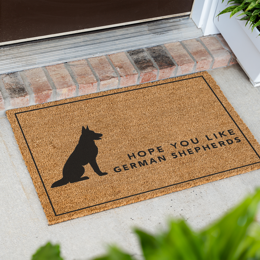 Hope You Like German Shepherds silhouette coir doormat with a thin black border at an angle in front of a brick step