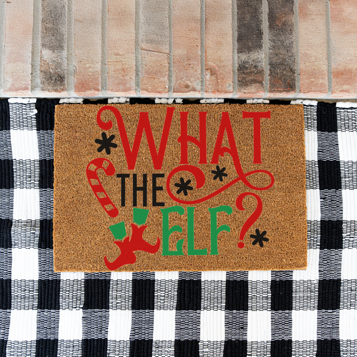 What The Elf coir doormat on a black and white buffalo check rug at a brick step