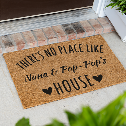 There's No Place Like Nana & Pop-Pop's House coir doormat at an angle on a front porch by a brick step