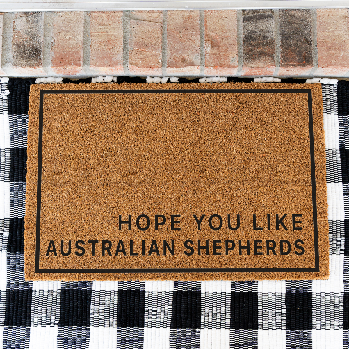 Hope You Like Australian Shepherds minimalist coir doormat with a thin black border on a black and white buffalo check rug, close view