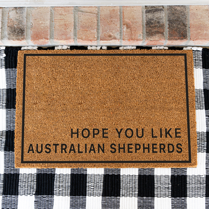 Hope You Like Australian Shepherds minimalist coir doormat with a thin black border on a black and white buffalo check rug, close view
