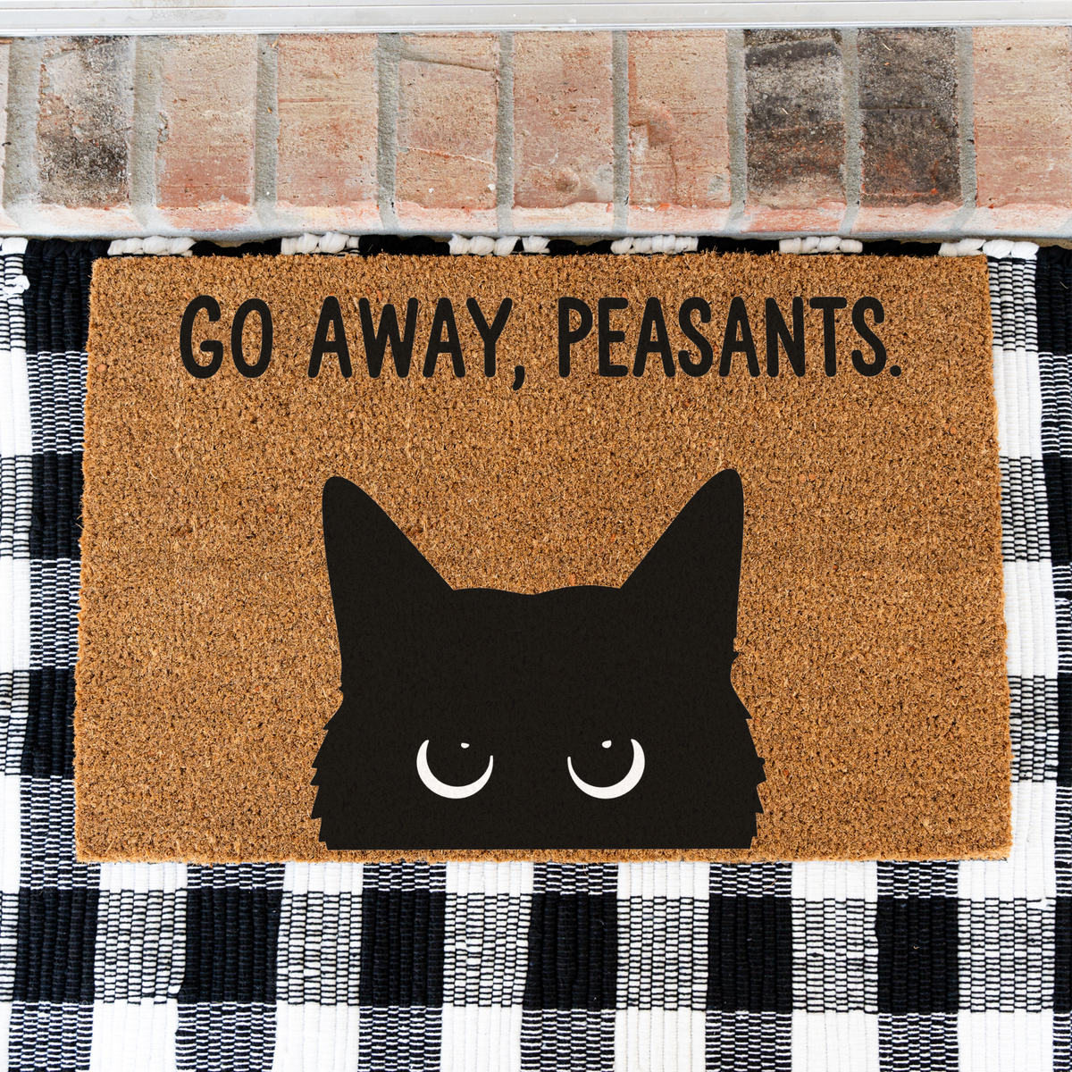 Go Away, Peasants black cat coir doormat on a black and white buffalo check rug, close view