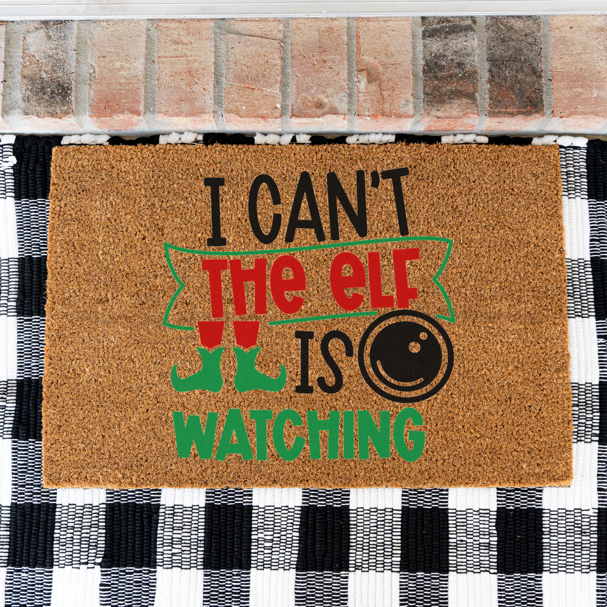 I Can't The Elf Is Watching coir doormat on a black and white buffalo check rug, close view