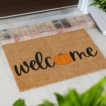 Welcome pumpkin coir doormat at an angle in front of a brick step