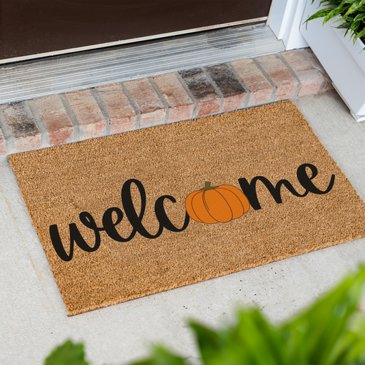 Welcome pumpkin coir doormat at an angle in front of a brick step