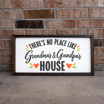 There's No Place Like Grandma's & Grandpa's House wide framed sign with a walnut frame leaning on a brick wall