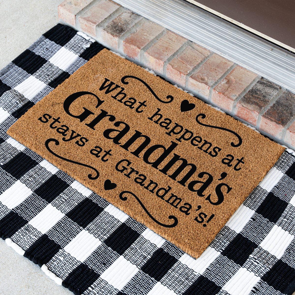 What Happens at Grandma's Stays at Grandma's coir doormat with hearts at an angle on a black and white buffalo check rug