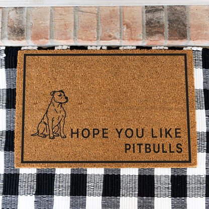 Hope You Like Pitbulls coir doormat with a drawing of a sitting pitbull on a black and white buffalo check rug, close view