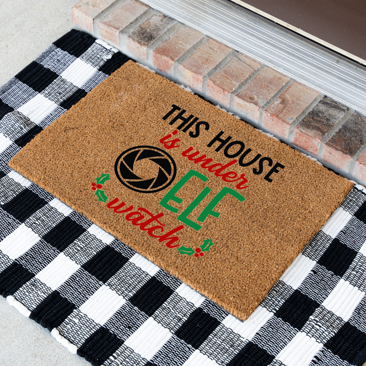 This House Is Under Elf Watch coir doormat at an angle on a black and white buffalo check rug