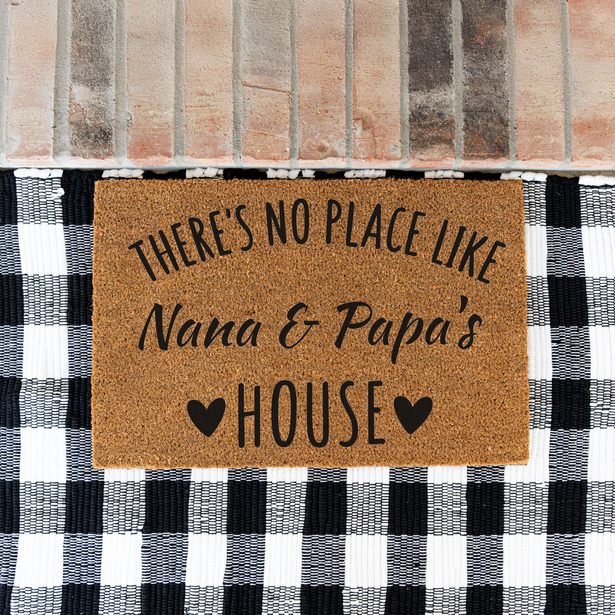 There's No Place Like Nana & Papa's House coir doormat on a black and white buffalo check rug at a brick step