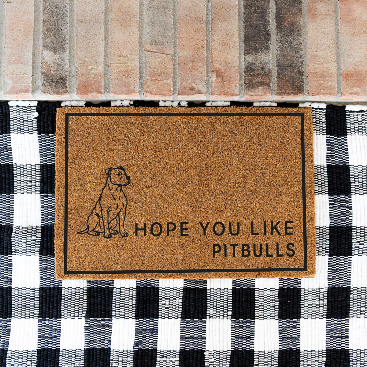 Hope You Like Pitbulls coir doormat with a drawing of a sitting pitbull on a black and white buffalo check rug at a brick step