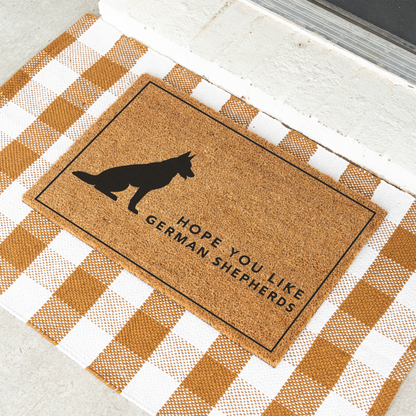 Hope You Like German Shepherds silhouette coir doormat with a thin black border on a tan and white check rug