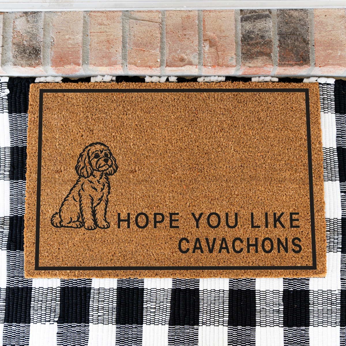 Hope You Like Cavachons coir doormat with a drawing of a sitting Cavachon on a black and white buffalo check rug, close view