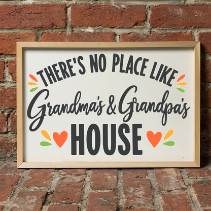 There's No Place Like Grandma's & Grandpa's House framed sign with a natural wood frame leaning on a red brick wall