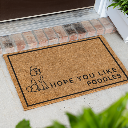 Hope You Like Poodles coir doormat with a drawing of a sitting poodle at an angle on a front porch by a brick step