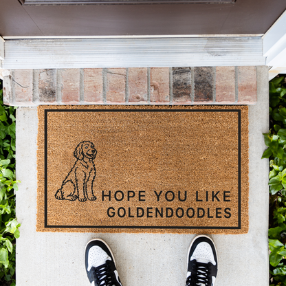 Hope You Like Goldendoodles coir doormat with a drawing of a sitting Goldendoodle in front of a brick step, top-down view with sneakers