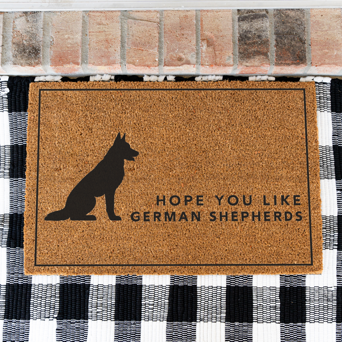 Hope You Like German Shepherds silhouette coir doormat with a thin black border on a black and white buffalo check rug, close view