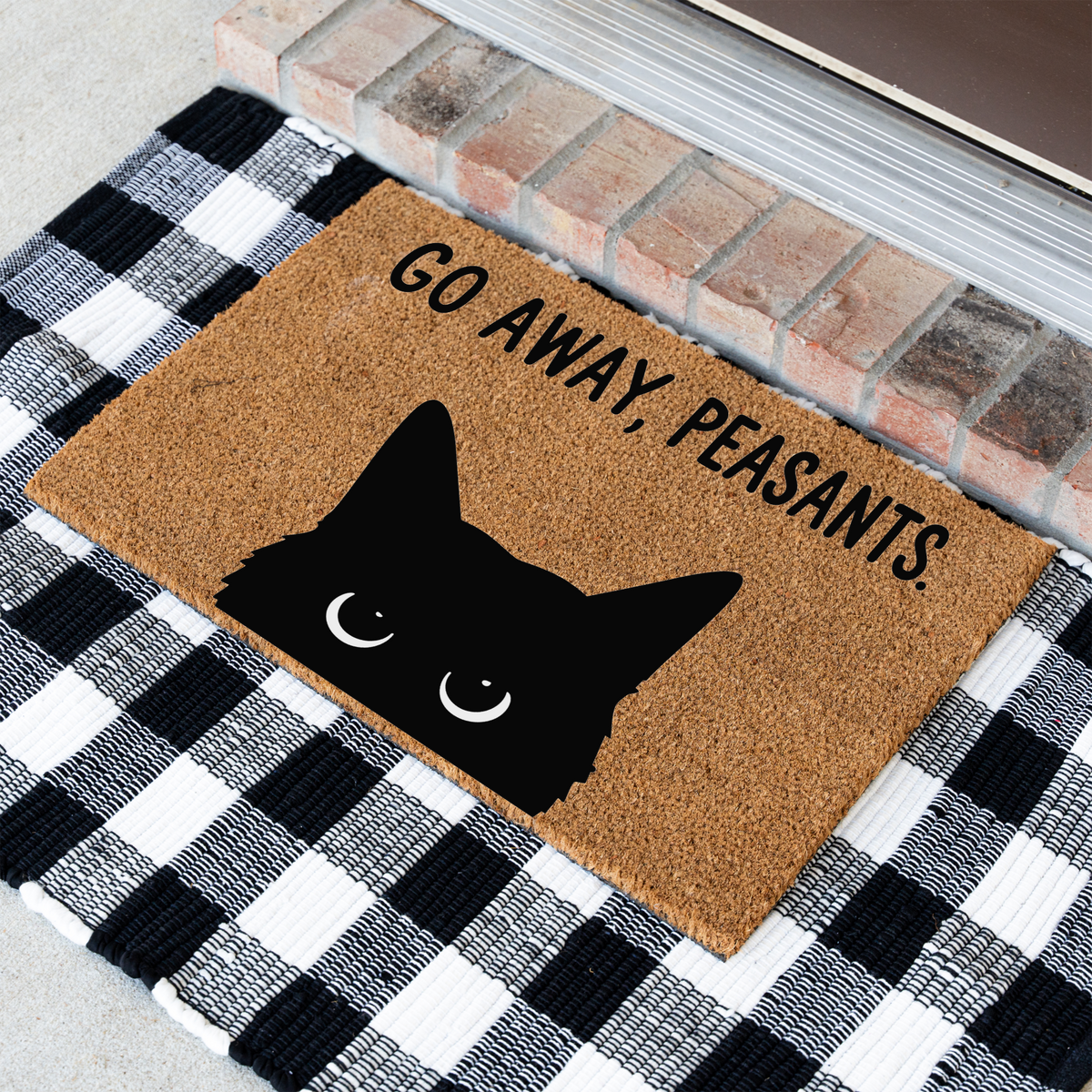 Go Away, Peasants black cat coir doormat at an angle on a black and white buffalo check rug