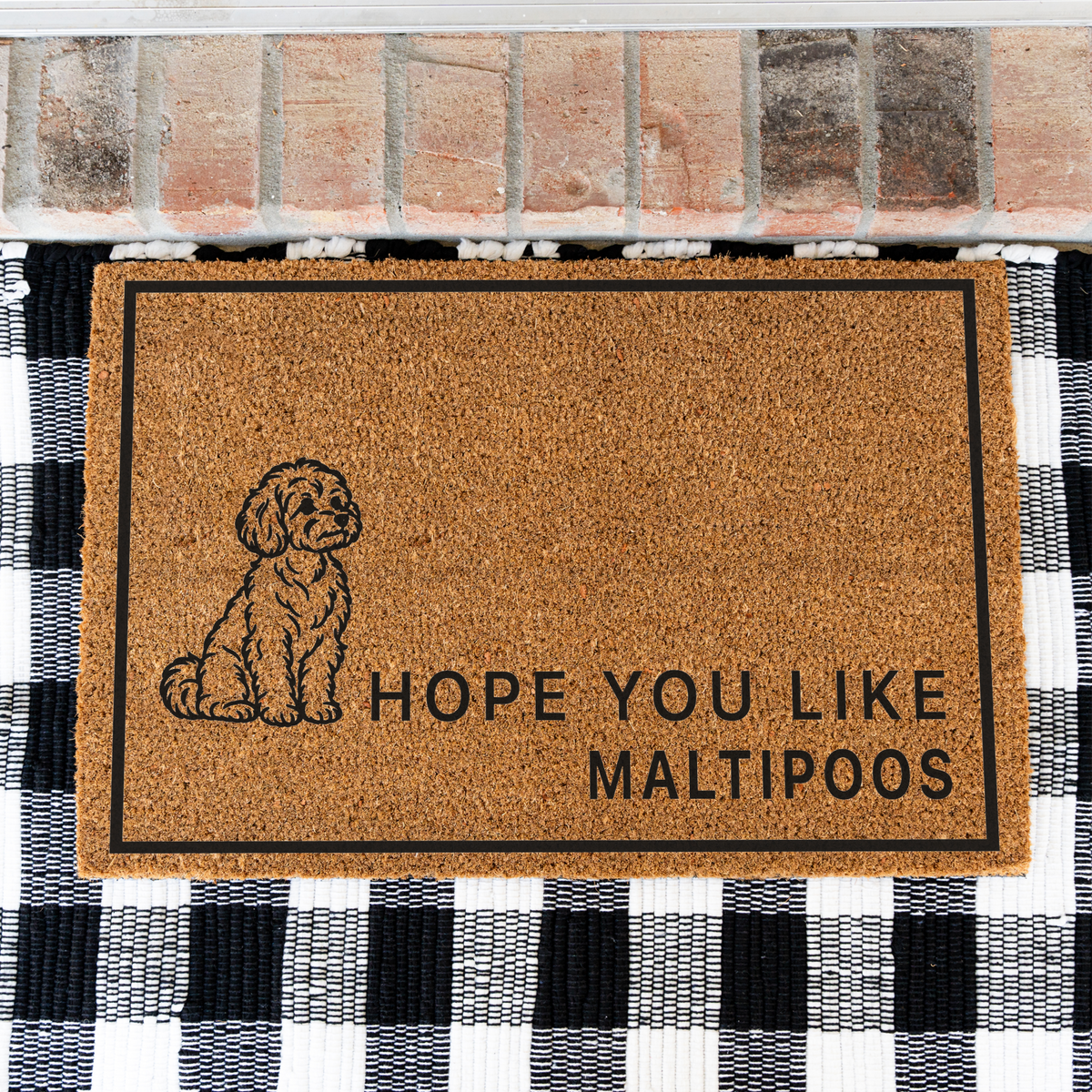 Hope You Like Maltipoos coir doormat with a drawing of a sitting Maltipoo on a black and white buffalo check rug, close view