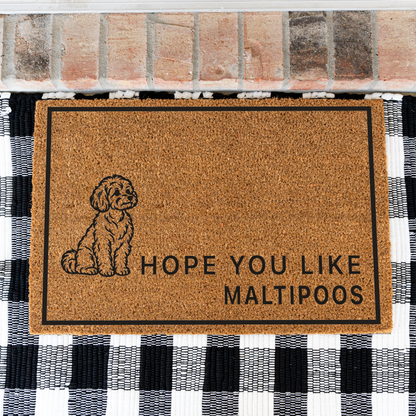 Hope You Like Maltipoos coir doormat with a drawing of a sitting Maltipoo on a black and white buffalo check rug, close view