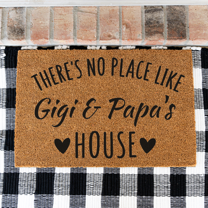 There's No Place Like Gigi & Papa's House coir doormat on a black and white buffalo check rug, close view