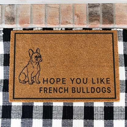 Hope You Like French Bulldogs coir doormat with a drawing of a sitting French bulldog on a black and white buffalo check rug, close view