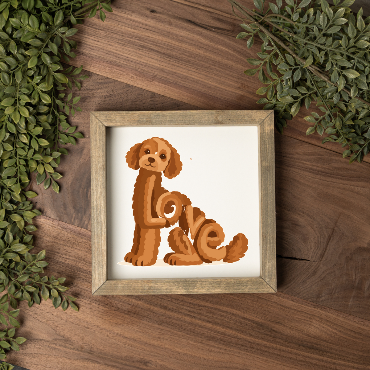 Sitting red doodle Love square framed sign with a weathered wood frame on a dark wood table with greenery