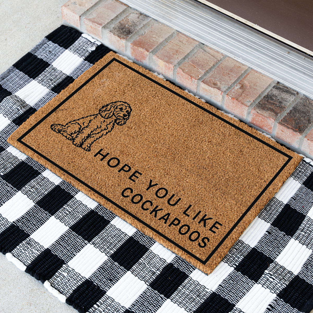 Hope You Like Cockapoos coir doormat with a drawing of a sitting Cockapoo at an angle on a black and white buffalo check rug