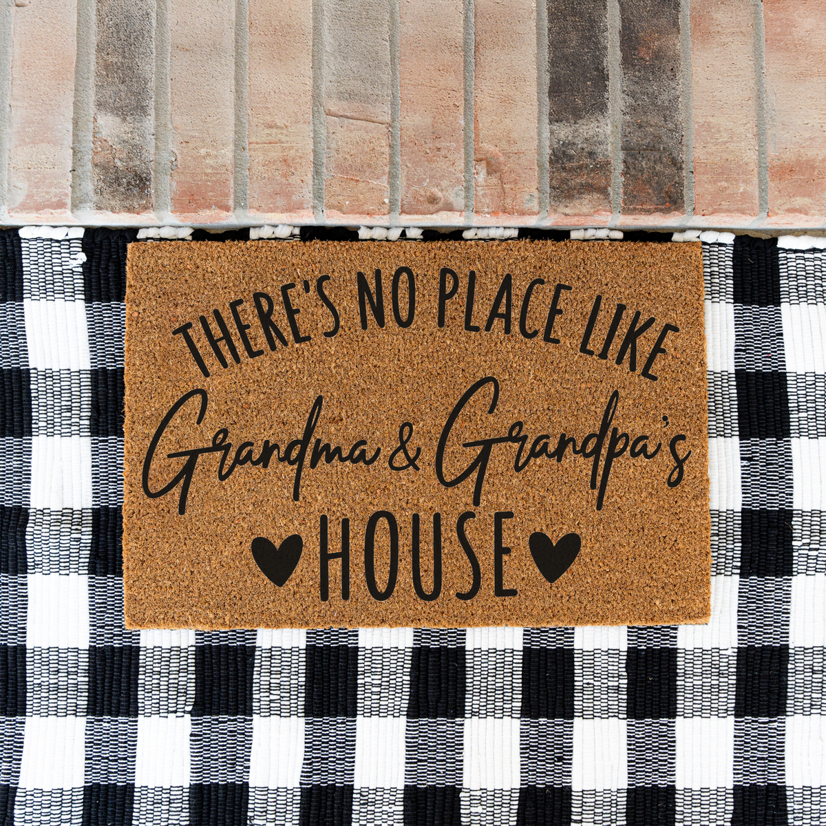 There's No Place Like Grandma & Grandpa's House coir doormat on a black and white buffalo check rug at a brick step