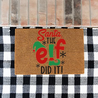 Santa The Elf Did It coir doormat on a black and white buffalo check rug at a brick step