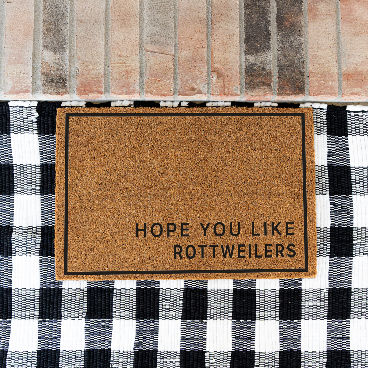 Hope You Like Rottweilers minimalist coir doormat with a thin black border on a black and white buffalo check rug at a brick step