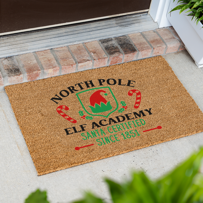 North Pole Elf Academy coir doormat at an angle in front of a brick step