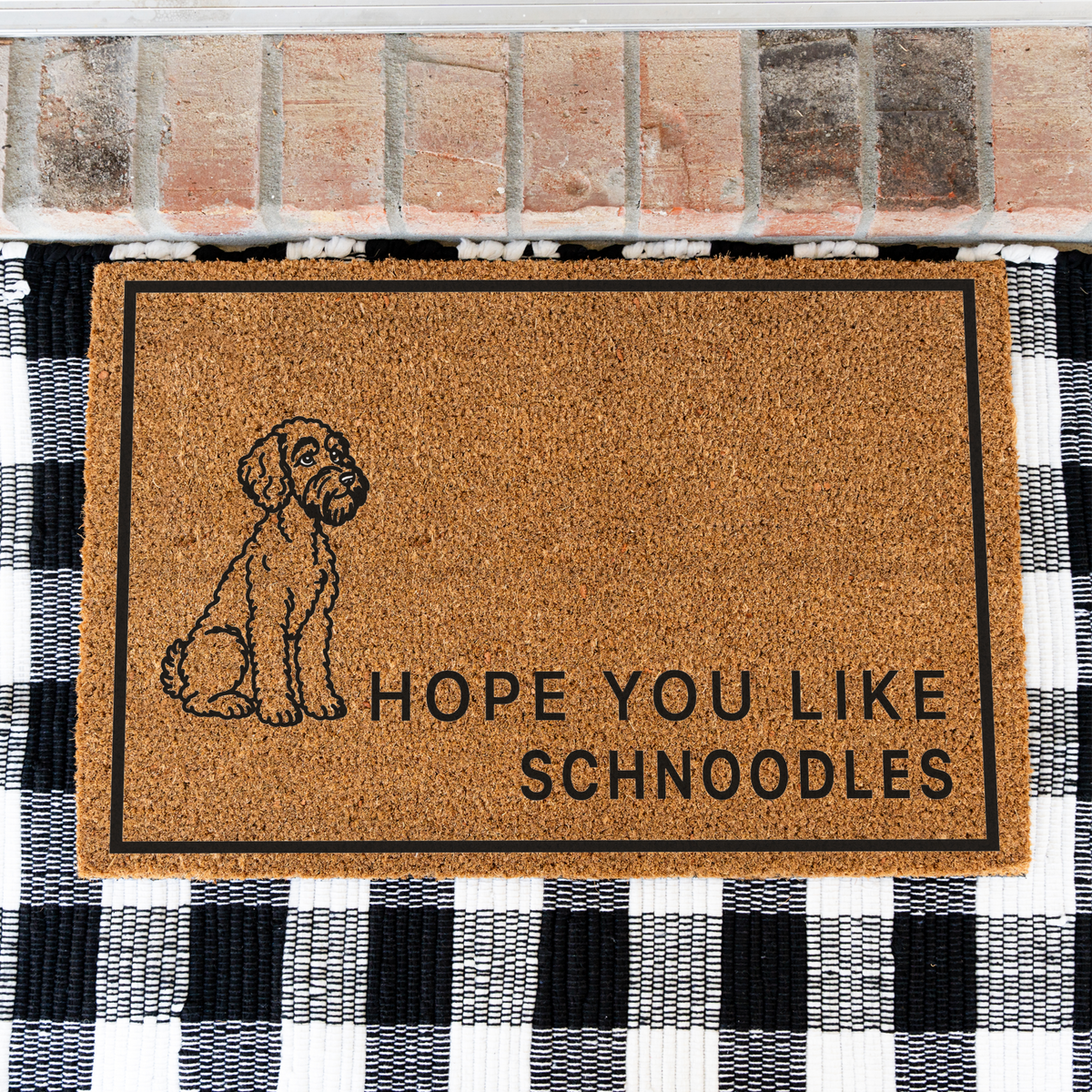 Hope You Like Schnoodles coir doormat with a drawing of a sitting Schnoodle on a black and white buffalo check rug, close view