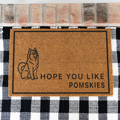 Hope You Like Pomskies coir doormat with a drawing of a sitting Pomsky on a black and white buffalo check rug, close view