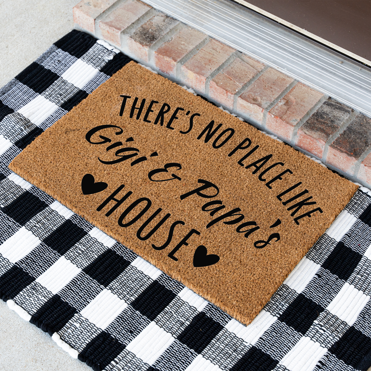 There's No Place Like Gigi & Papa's House coir doormat at an angle on a black and white buffalo check rug