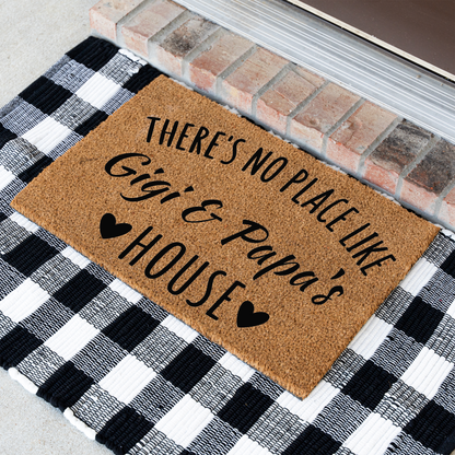 There's No Place Like Gigi & Papa's House coir doormat at an angle on a black and white buffalo check rug
