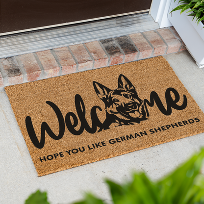 Welcome Hope You Like German Shepherds coir doormat with a German shepherd head in the word welcome at an angle in front of a brick step