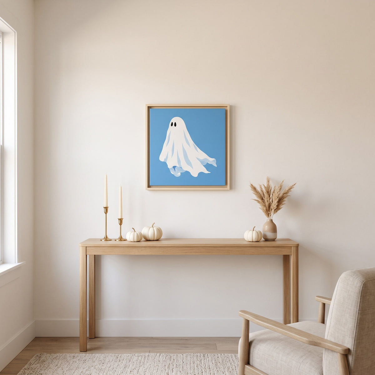 Blue ghost framed canvas print, 20 x 20 inch size, hanging above a light oak console table with white pumpkins