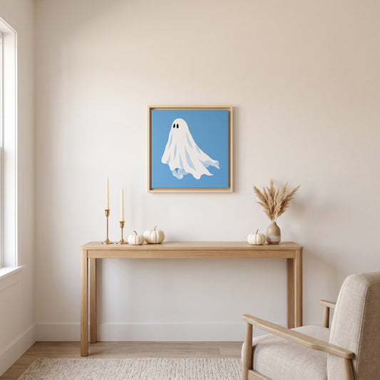 Blue ghost framed canvas print, 20 x 20 inch size, hanging above a light oak console table with white pumpkins